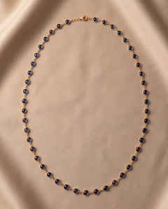 14K yellow gold cabochon kyanite station necklace laid flat on champagne silk