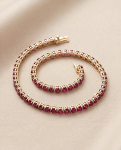 Ruby and diamond line bracelet in 14K yellow gold, coiled on silk