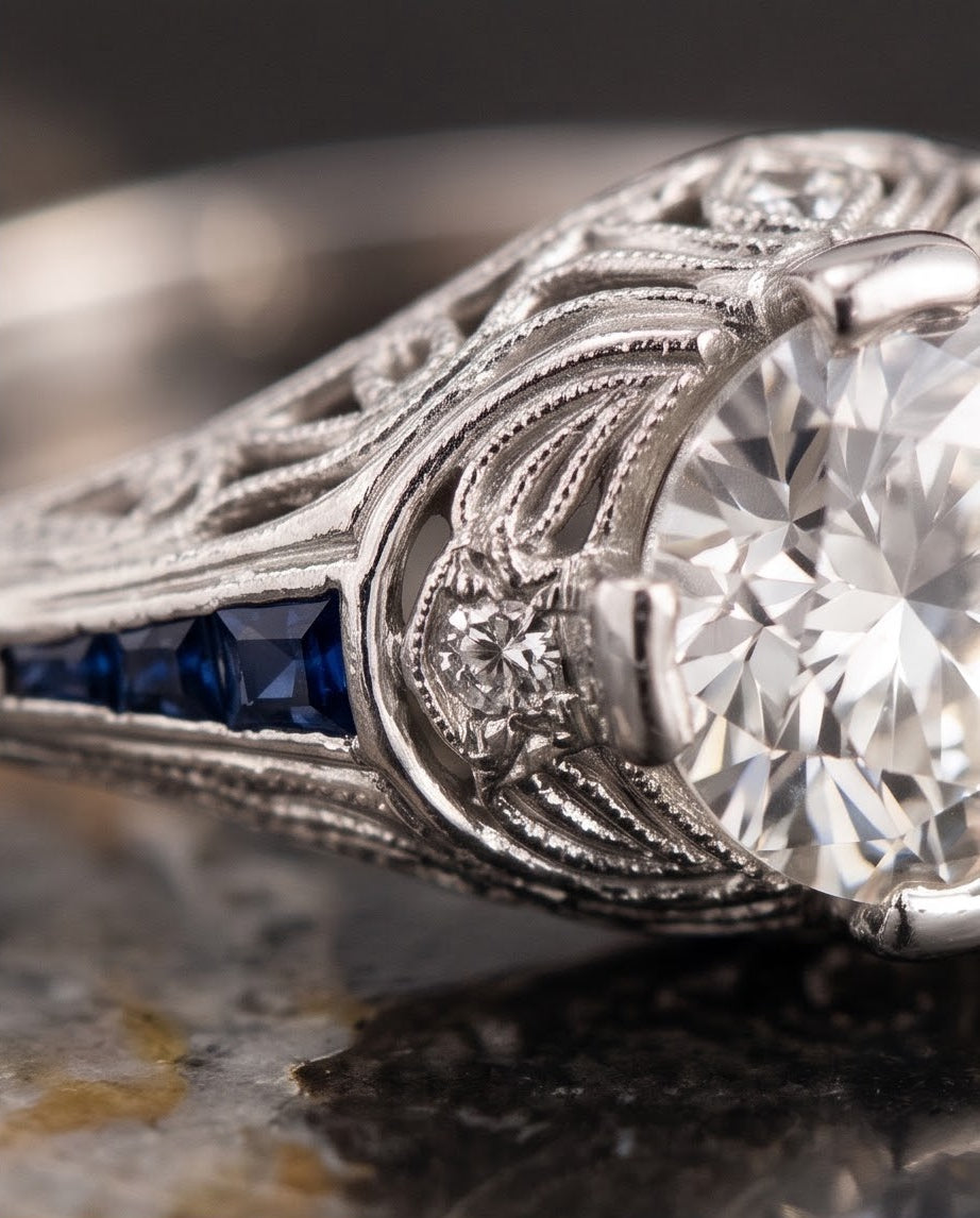 Macro detail of the platinum filigree gallery, milgrain edging, bead-set diamond accent and channel-set French-cut sapphires