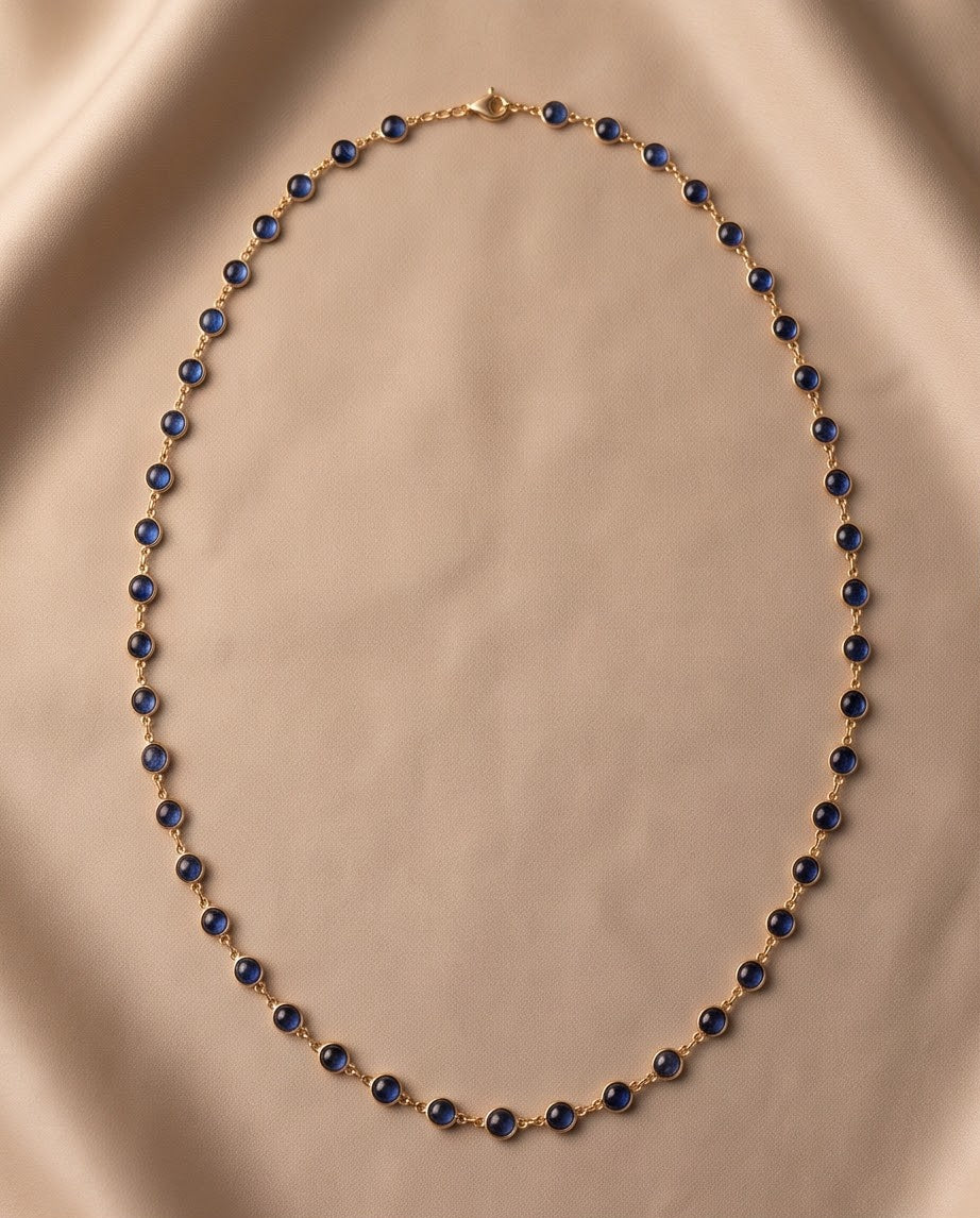 14K yellow gold cabochon kyanite station necklace laid flat on champagne silk