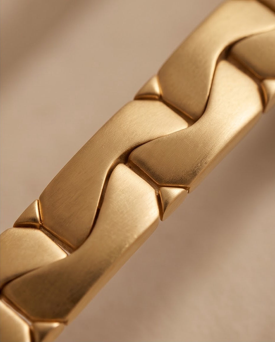 Macro detail of the wide sculpted 18K gold links showing matte surfaces and high polish edges