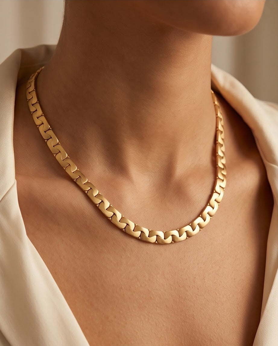 18K gold interlocking link collar necklace worn at the base of the neck with an open ivory collar