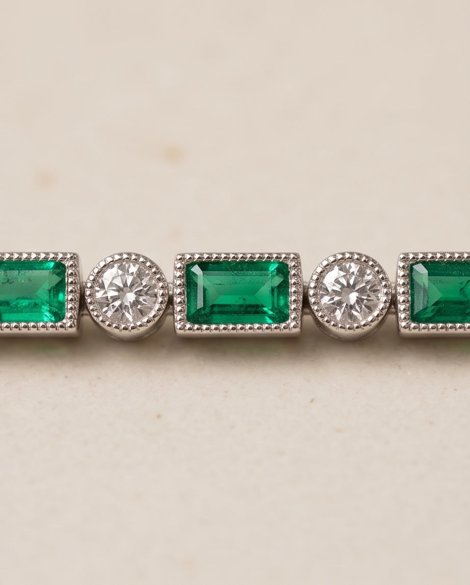 Close-up of milgrain bezel-set emerald-cut emeralds and round diamonds