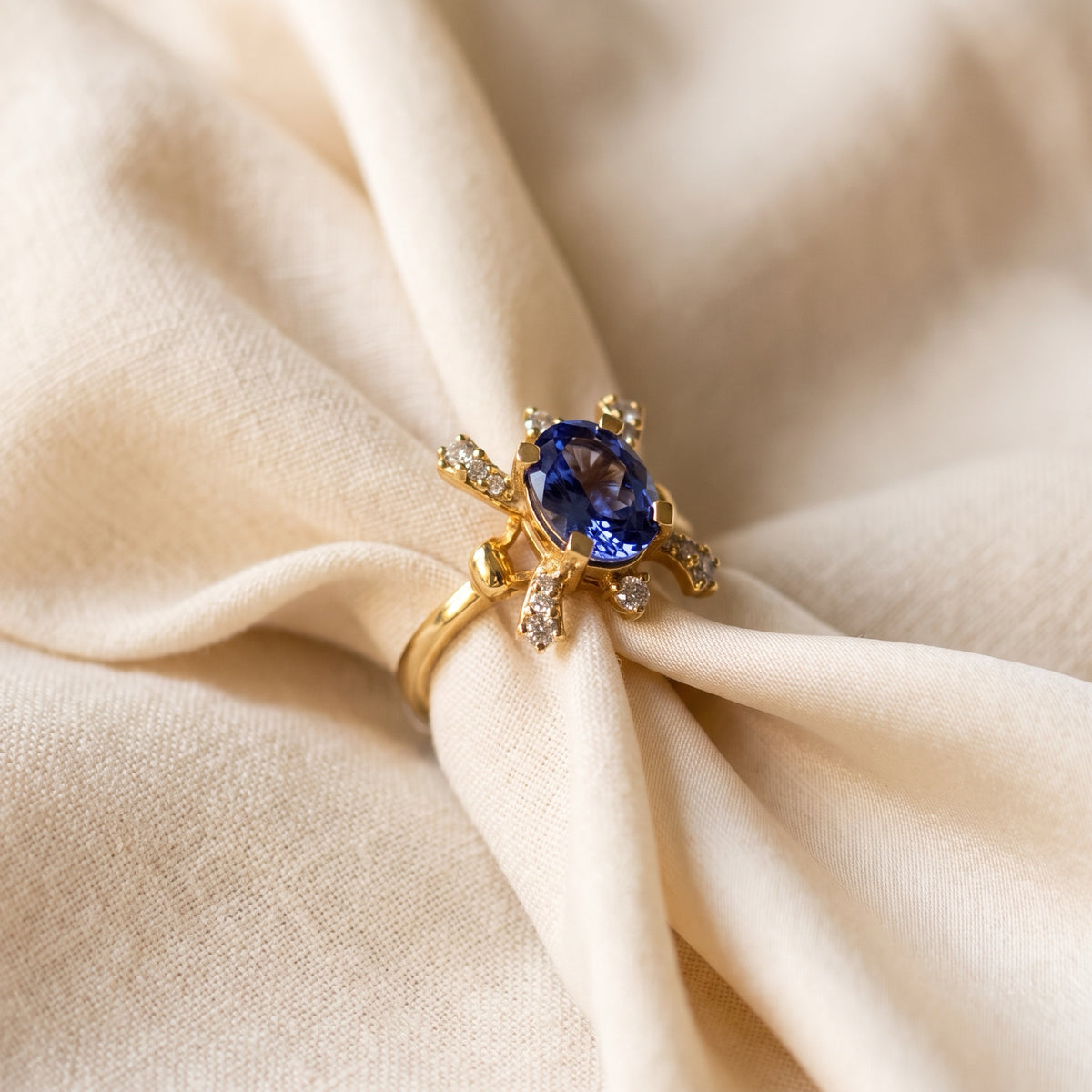 Tanzanite and diamond starburst ring resting on ivory silk