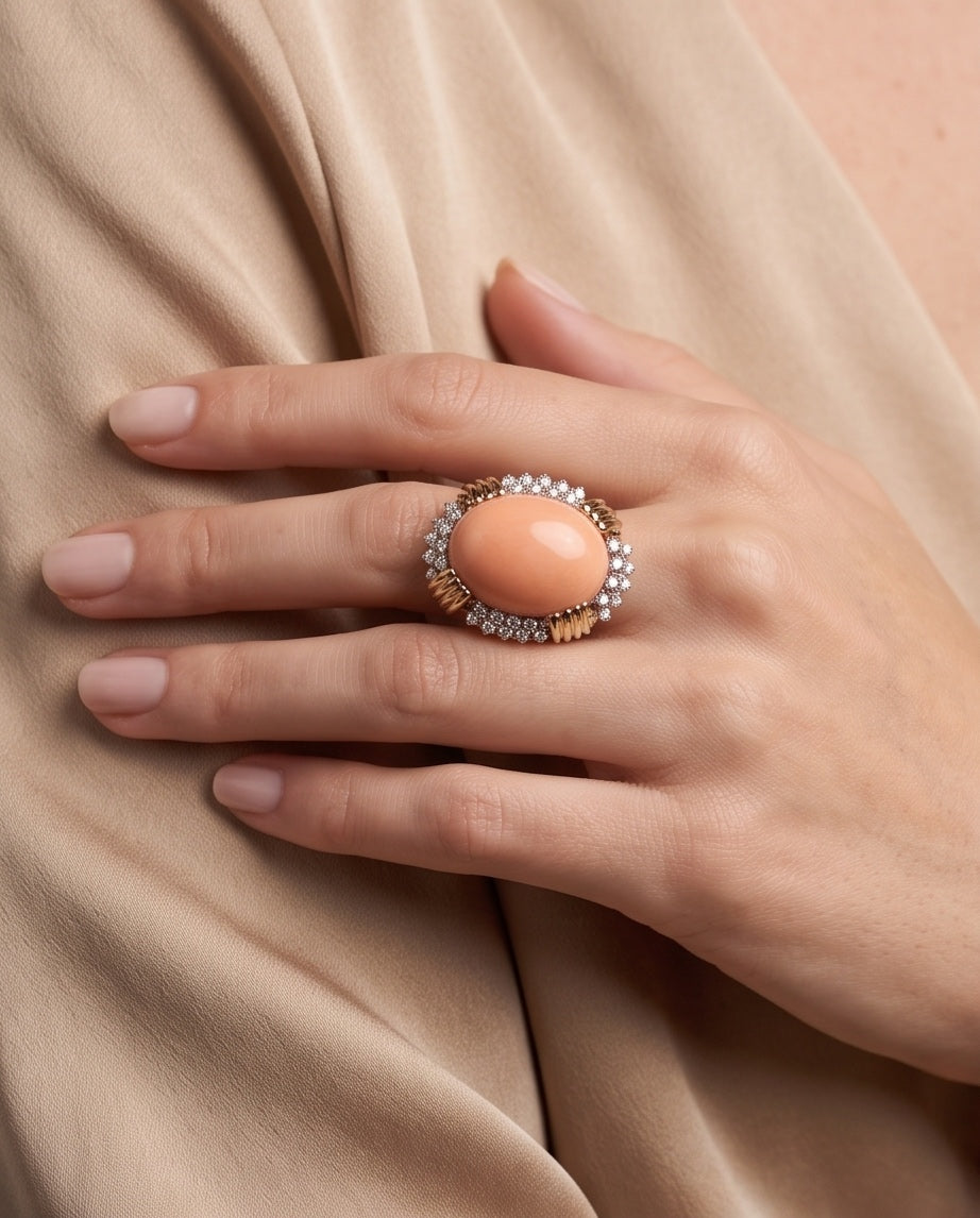 Close-up of angel skin coral diamond ring worn on hand