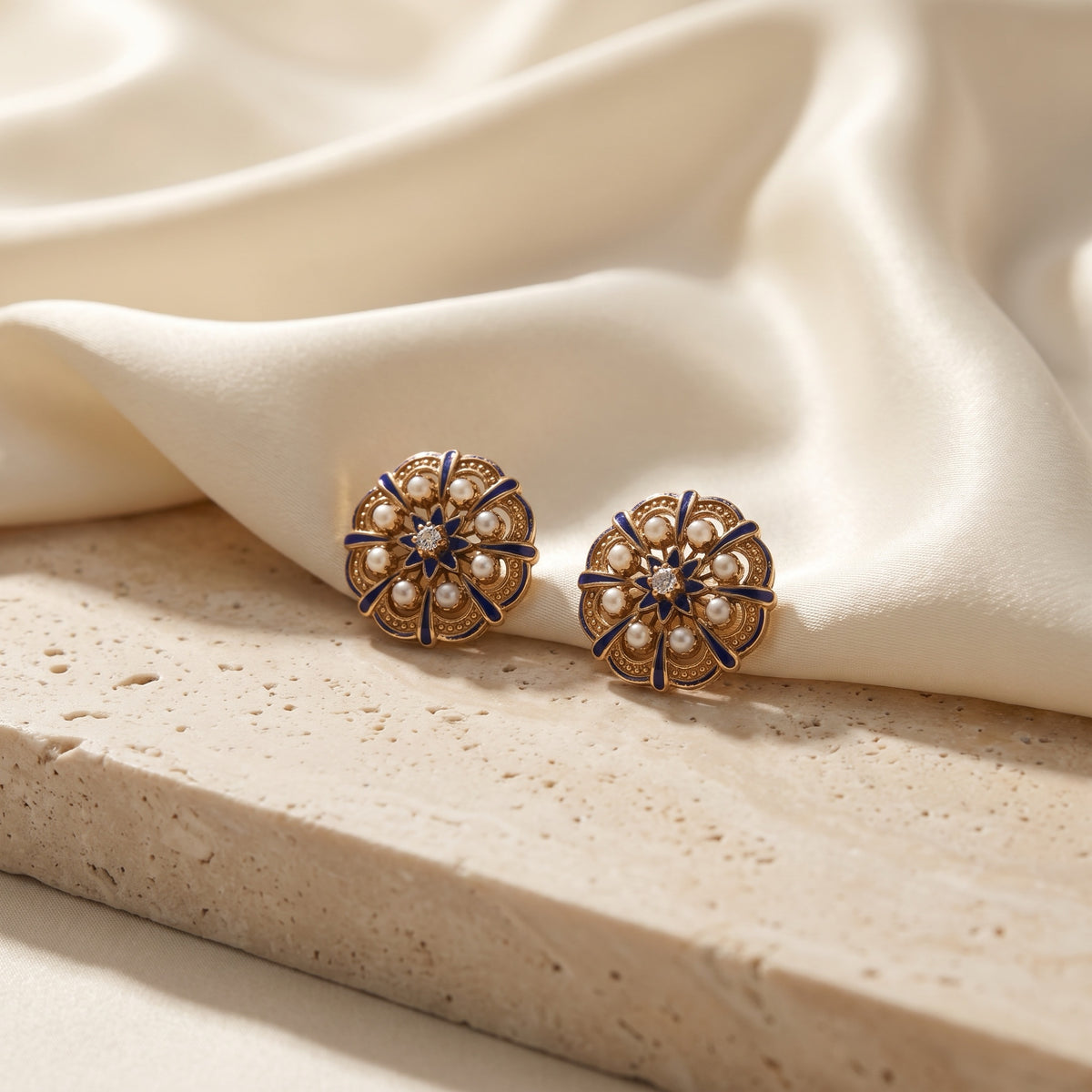 14kt gold blue enamel and seed pearl rosette earrings with diamond centers on ivory silk