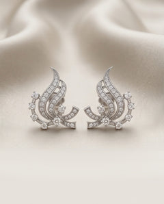 14K white gold diamond swirl earrings on cream silk