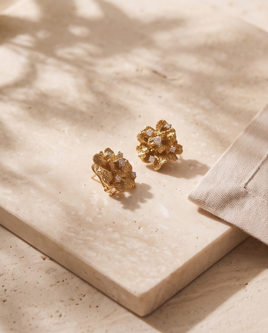 Pair of coral flower diamond earrings styled on marble with linen