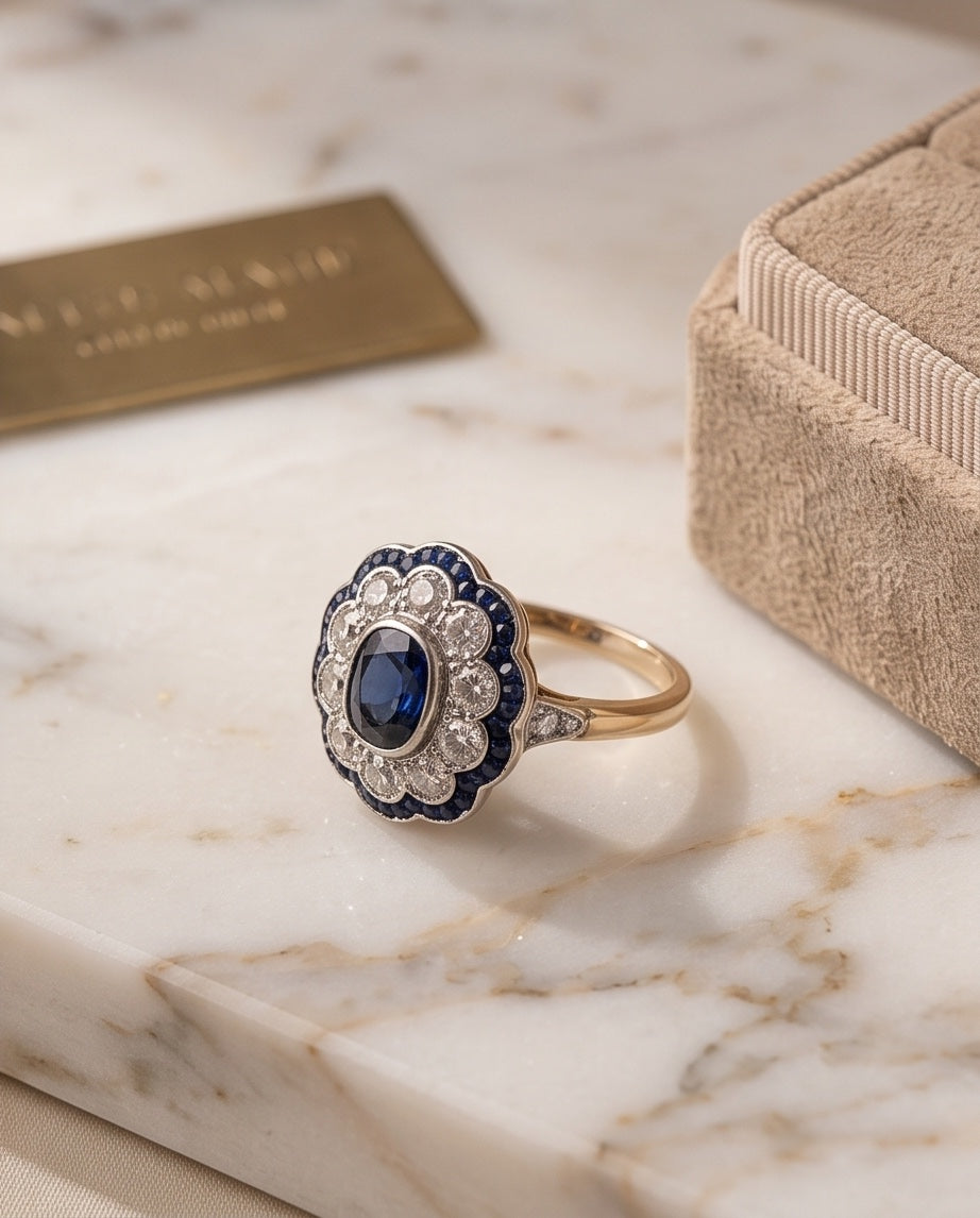 Sapphire and diamond cluster ring displayed on marble with jewelry box