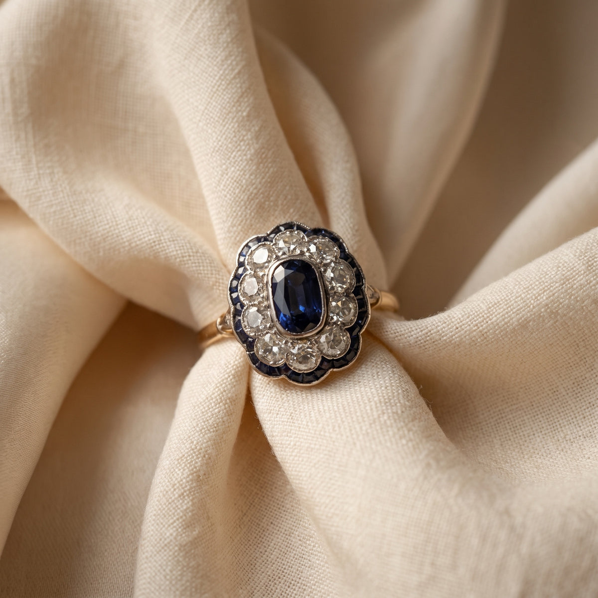Macro close-up of sapphire and diamond cluster ring on linen